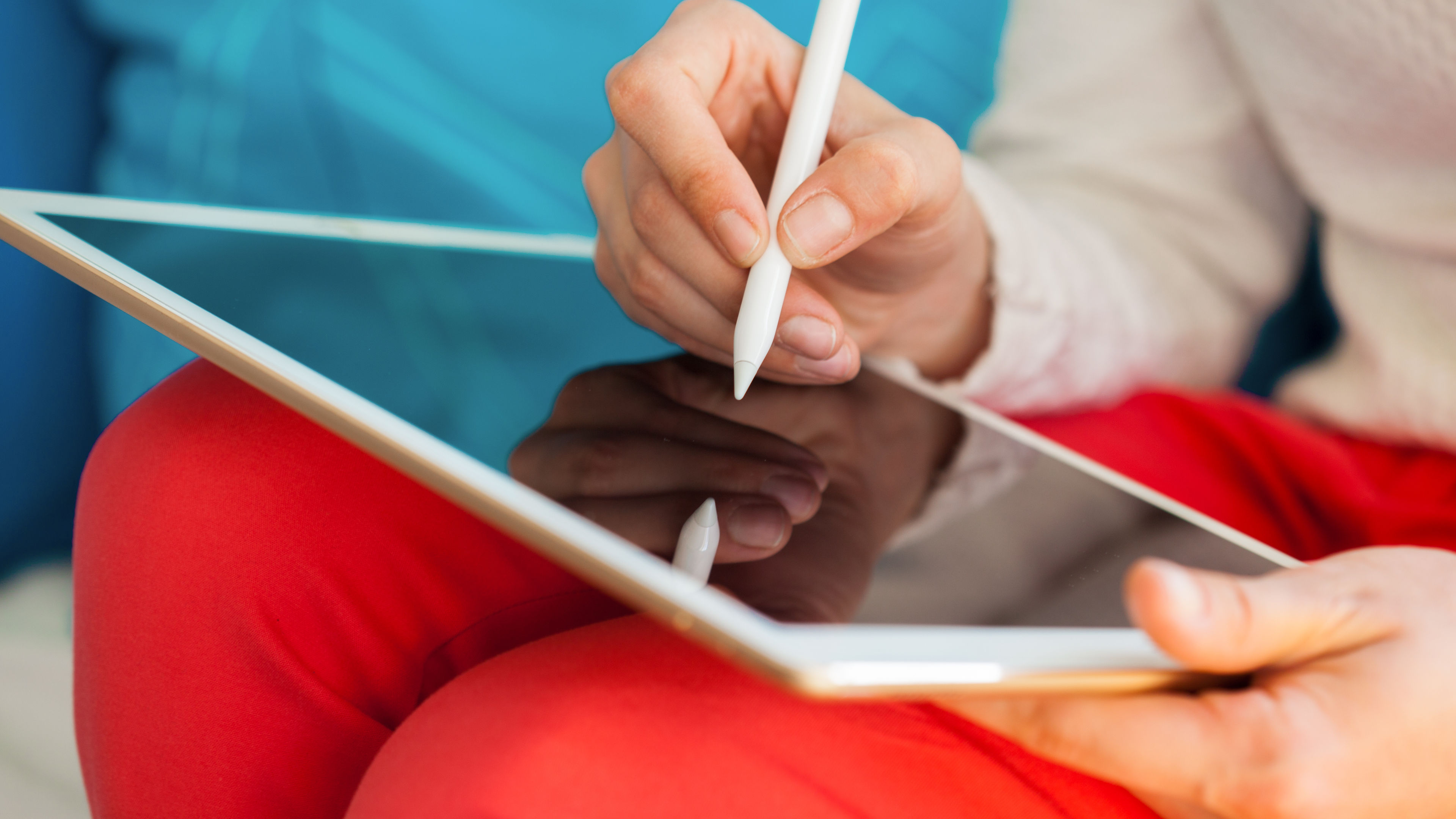 Taong nagsusulat sa isang digital tablet gamit ang isang puting stylus.