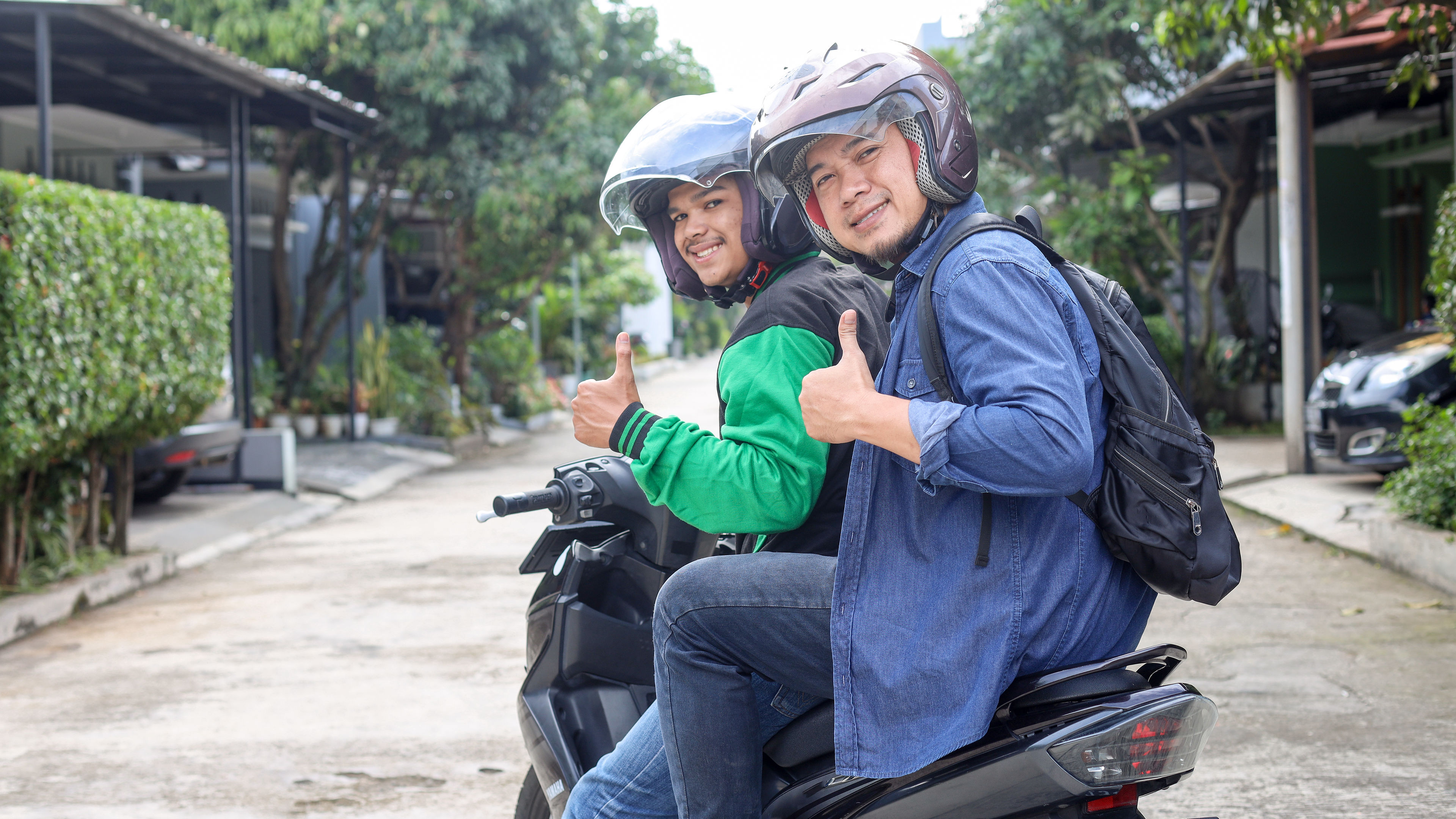 Dalawang lalaking Pinoy na naka scooter, nakangiti at nagbigay ng hinlalaki.