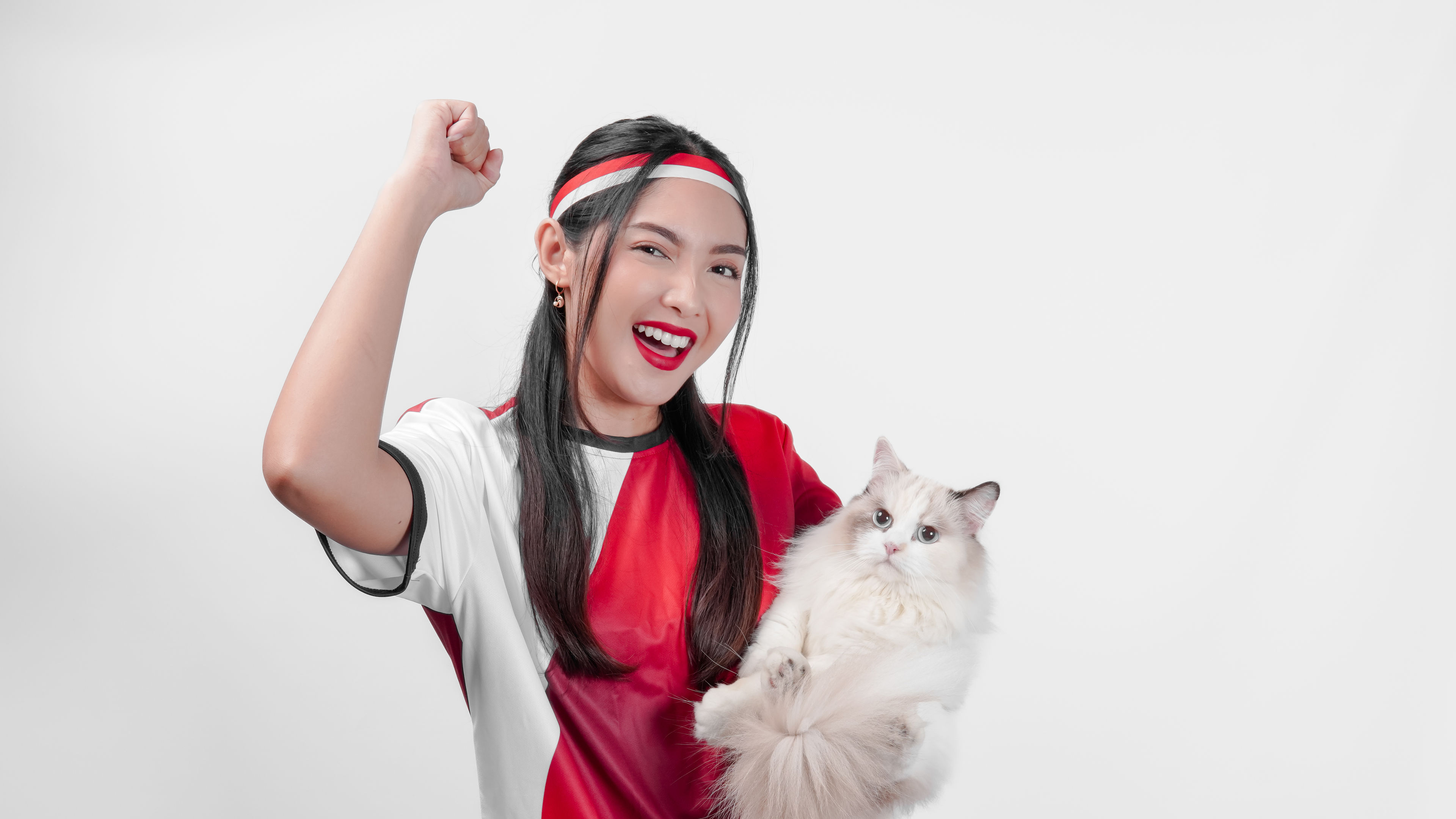 A cheerful young woman wearing a red and white sports jersey