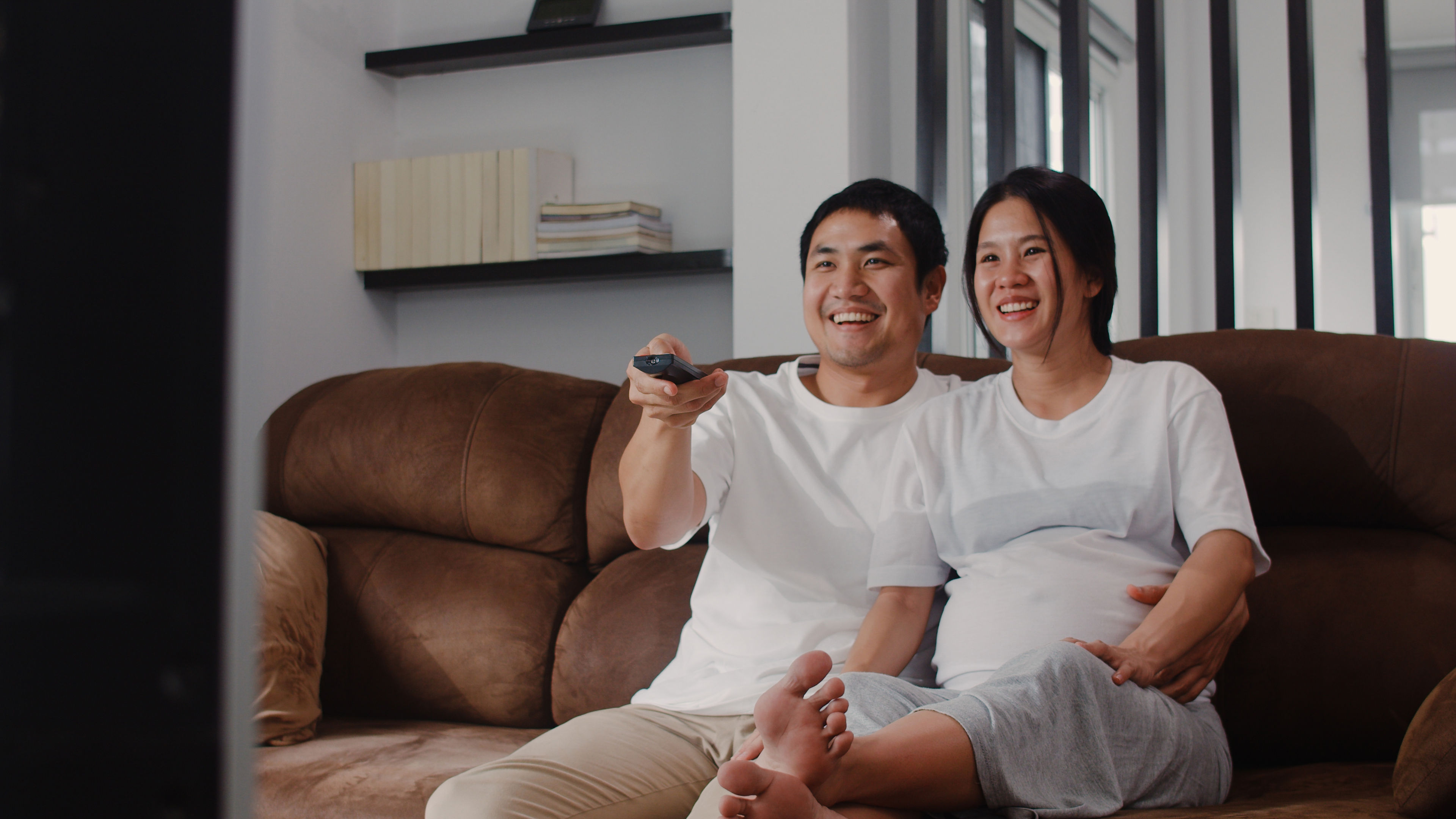 A couple holding a remote in hand 