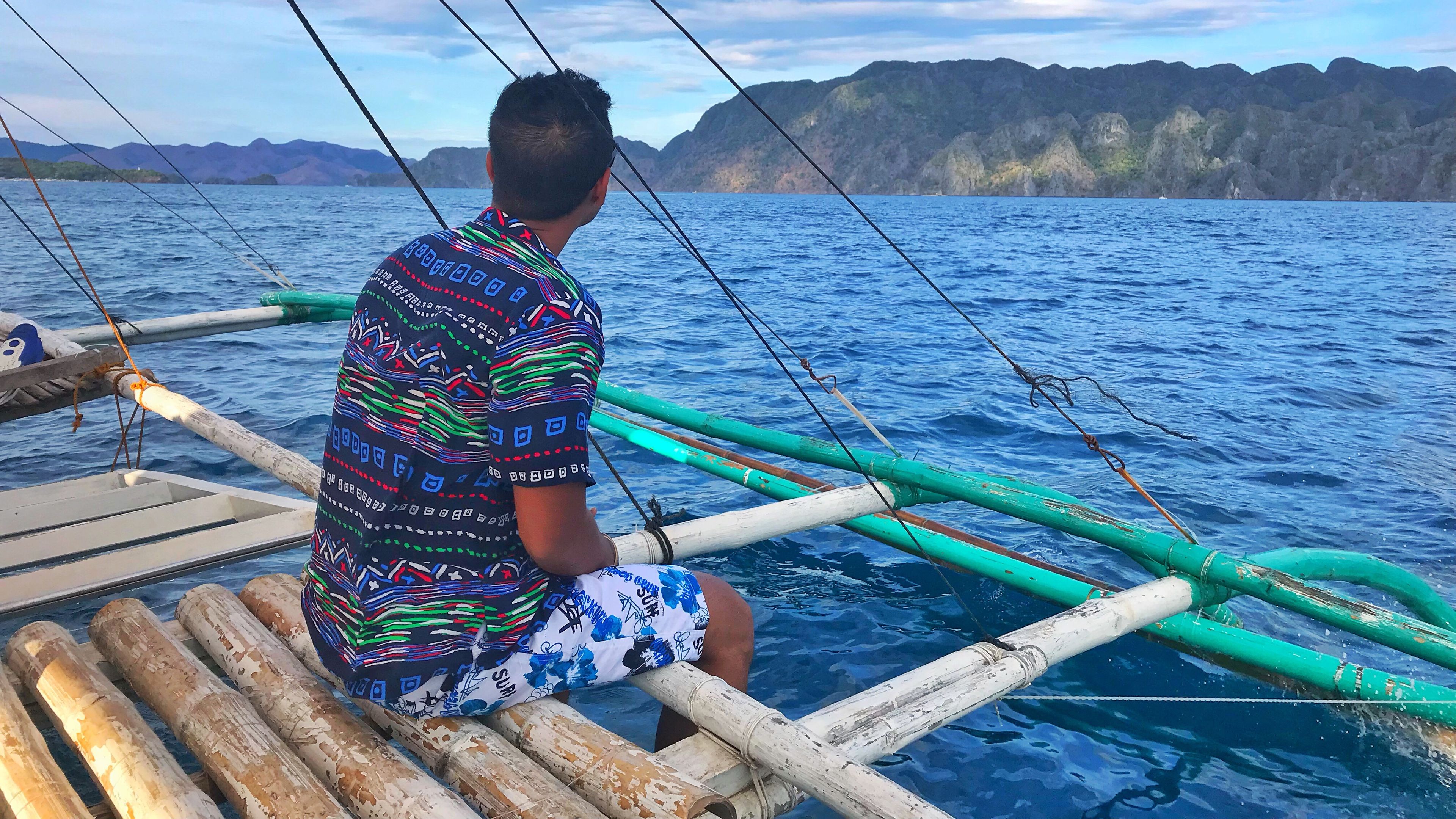 A man enjoying the ocean from a wooden boat 