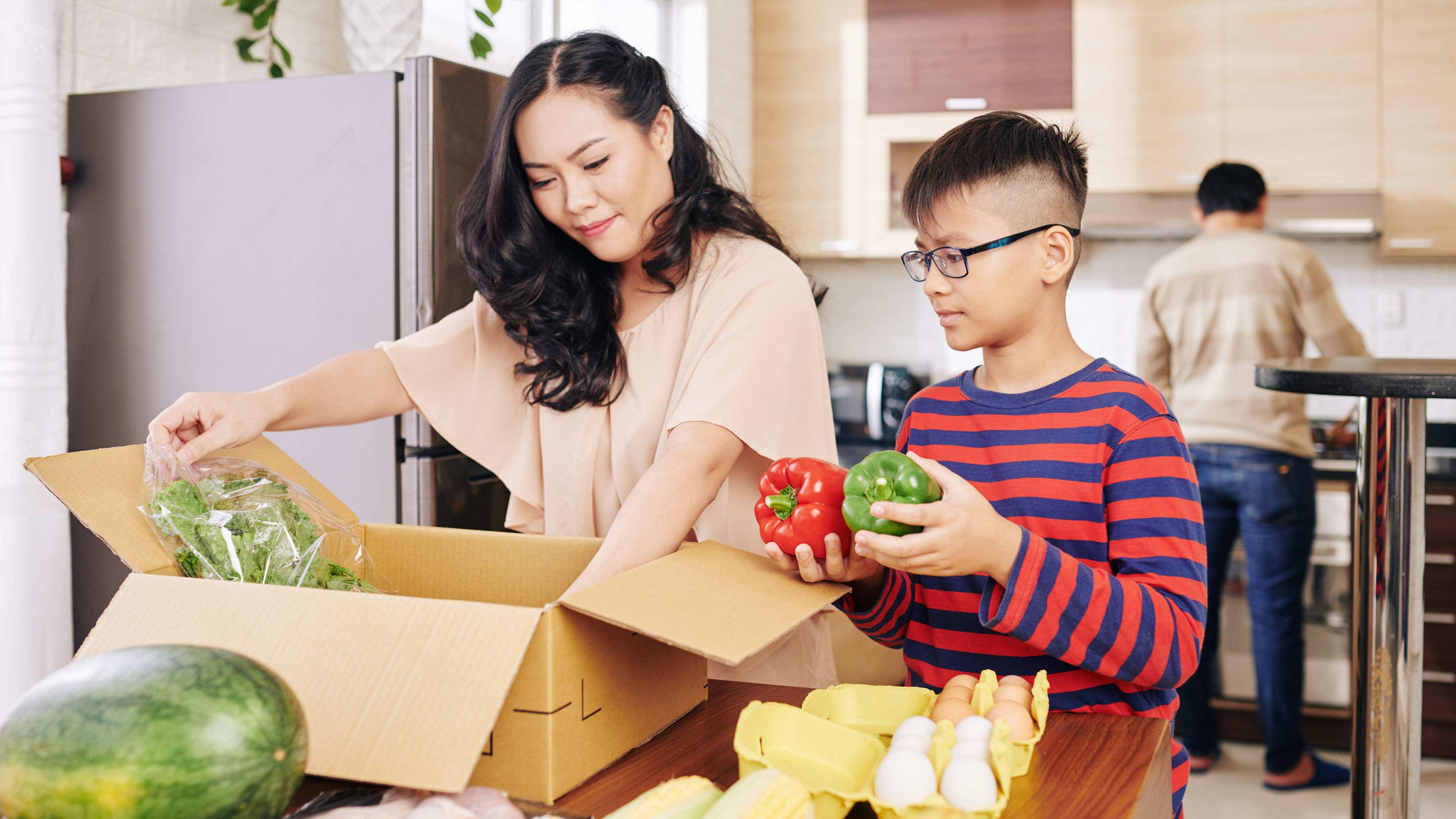 A mother and a son unboxing groceries. 