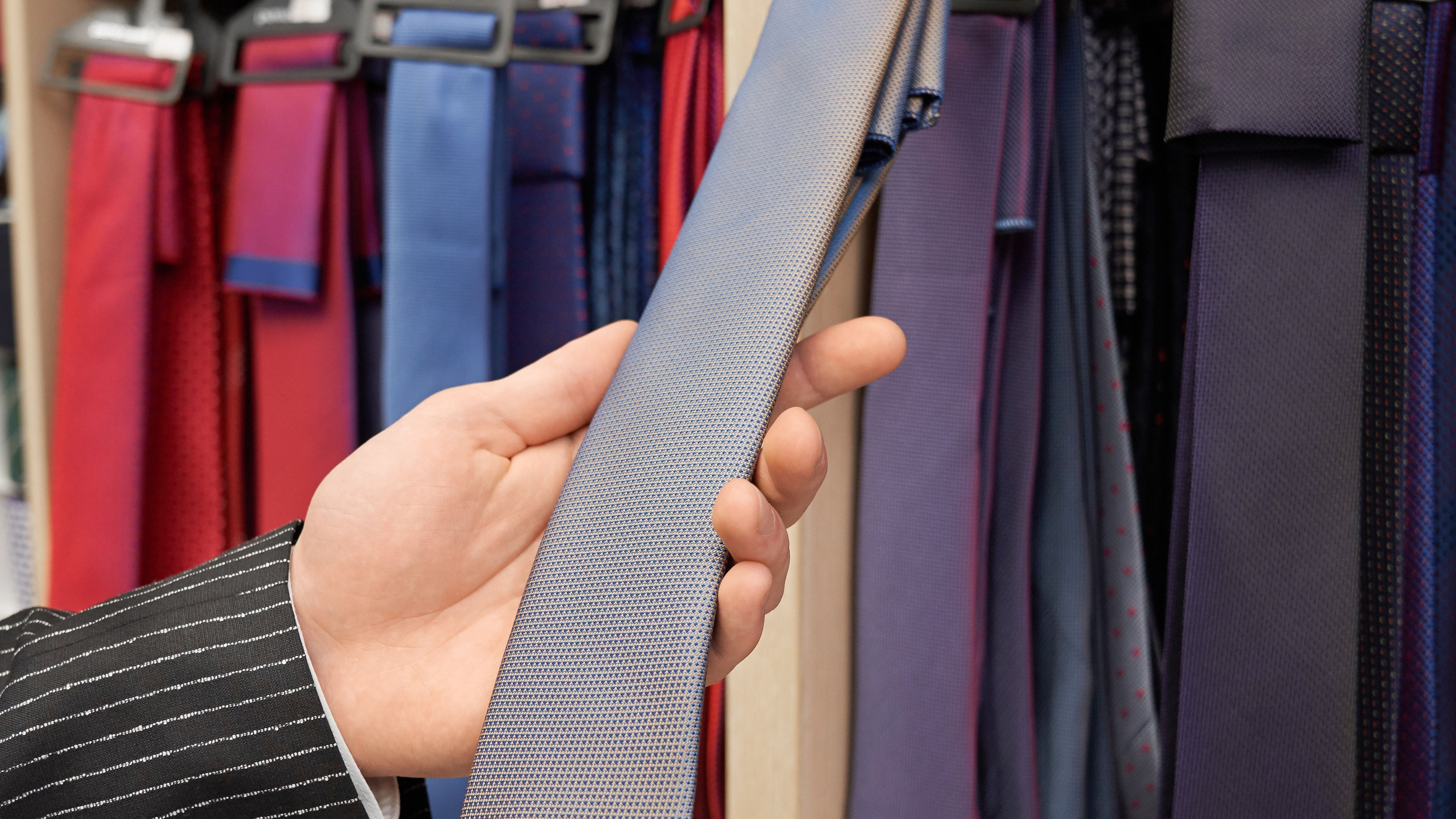 Close-up of male hand holding, showing grey necktie. 

 