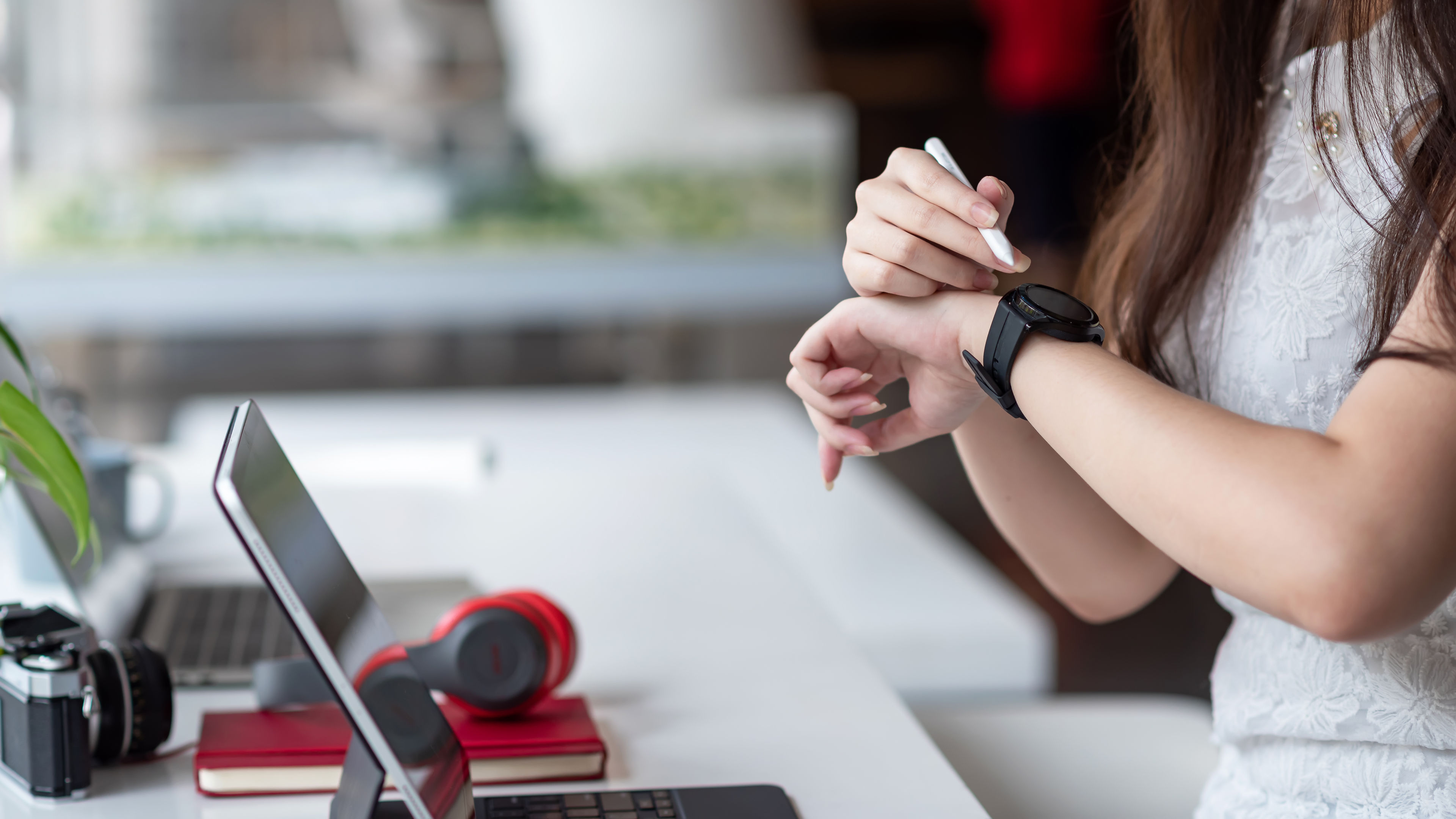 Close-up of a woman hand holding a pen and looking at a wristwatch. 

 