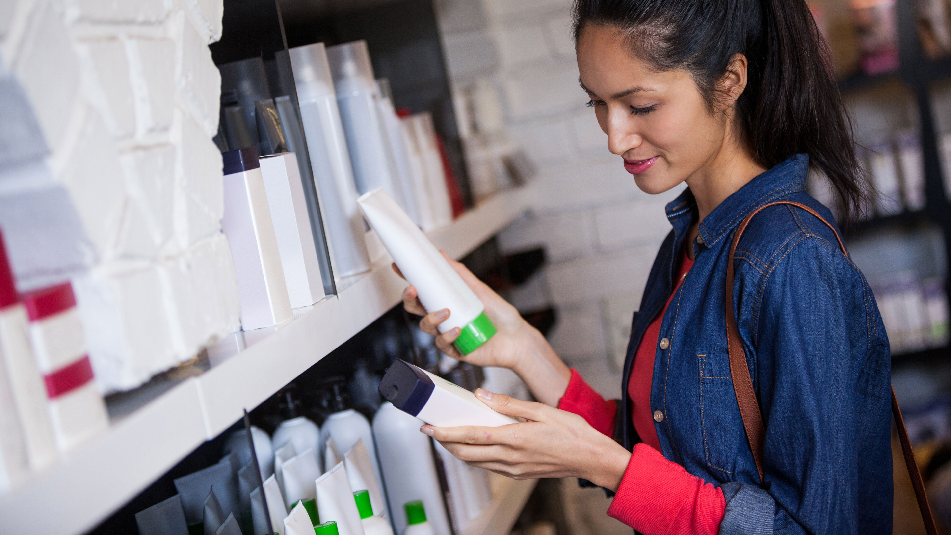 Female hairdresser selecting shampoo from shelf at a salon 