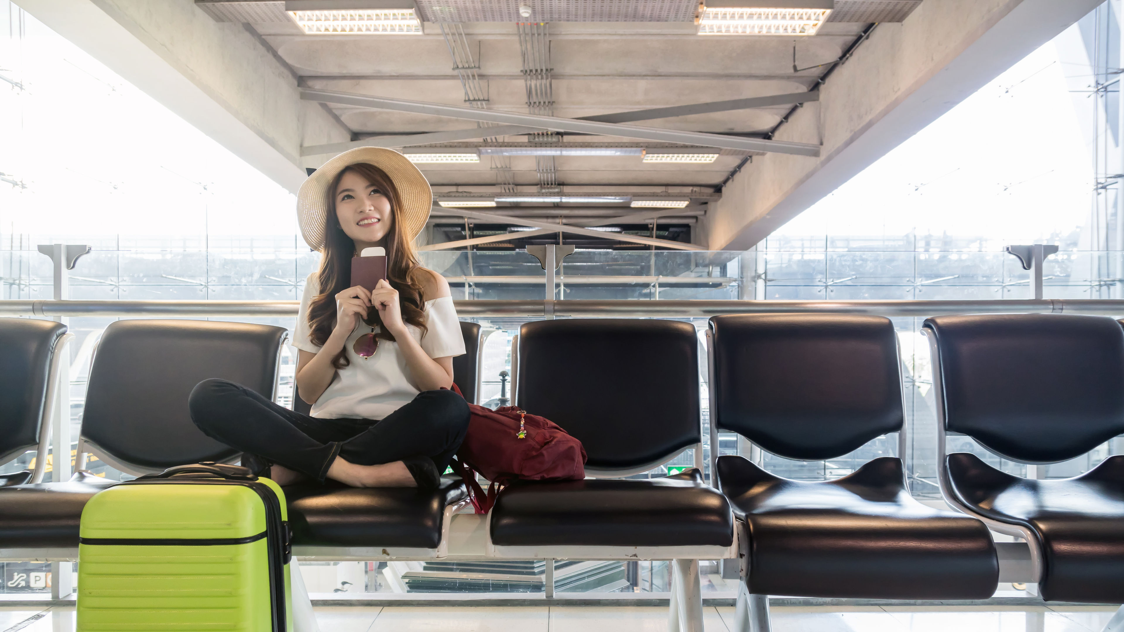 Happy Asian woman traveler holding the passport with suitcases in modern an airport 