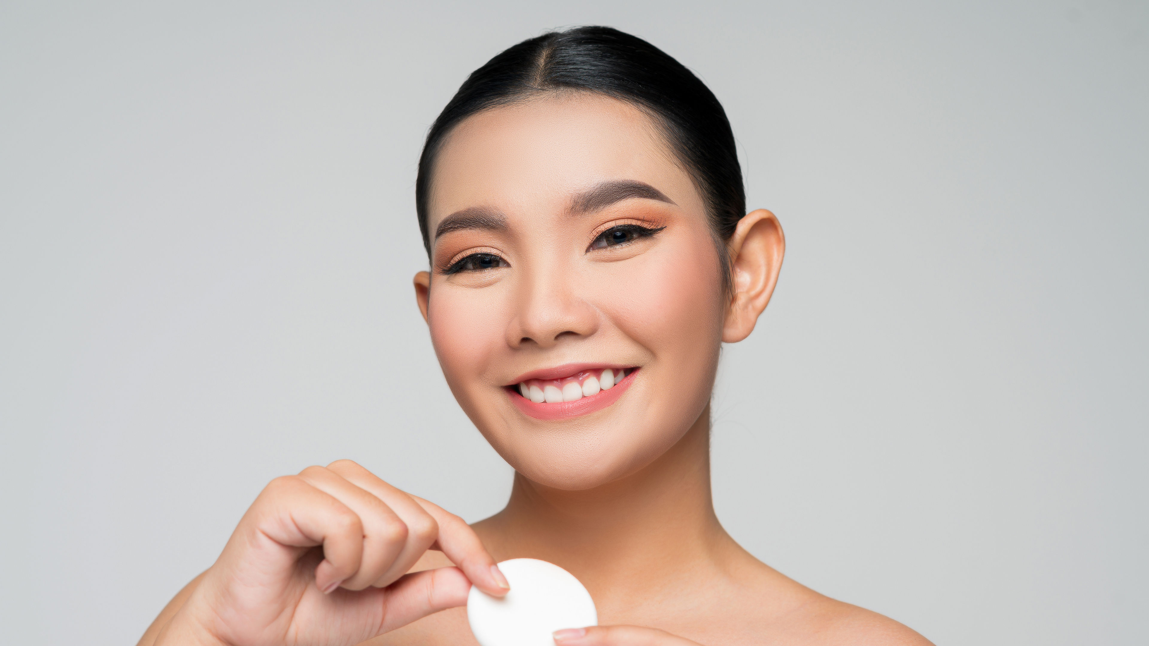A young beautiful asian woman smiling by holding a sponge in her hand 
