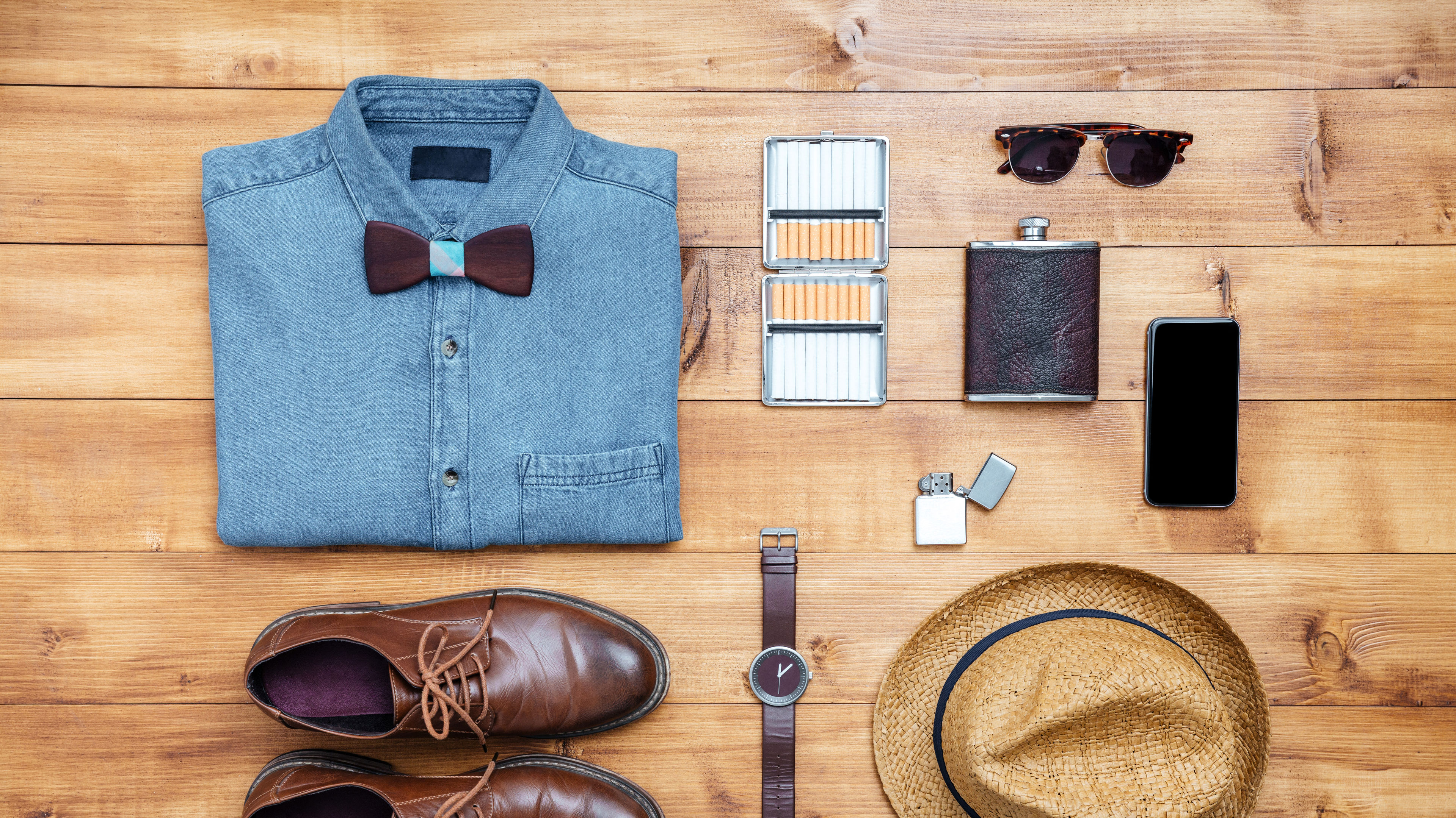 Some men’s accessories like shoes, watches etc on a wooden table. 