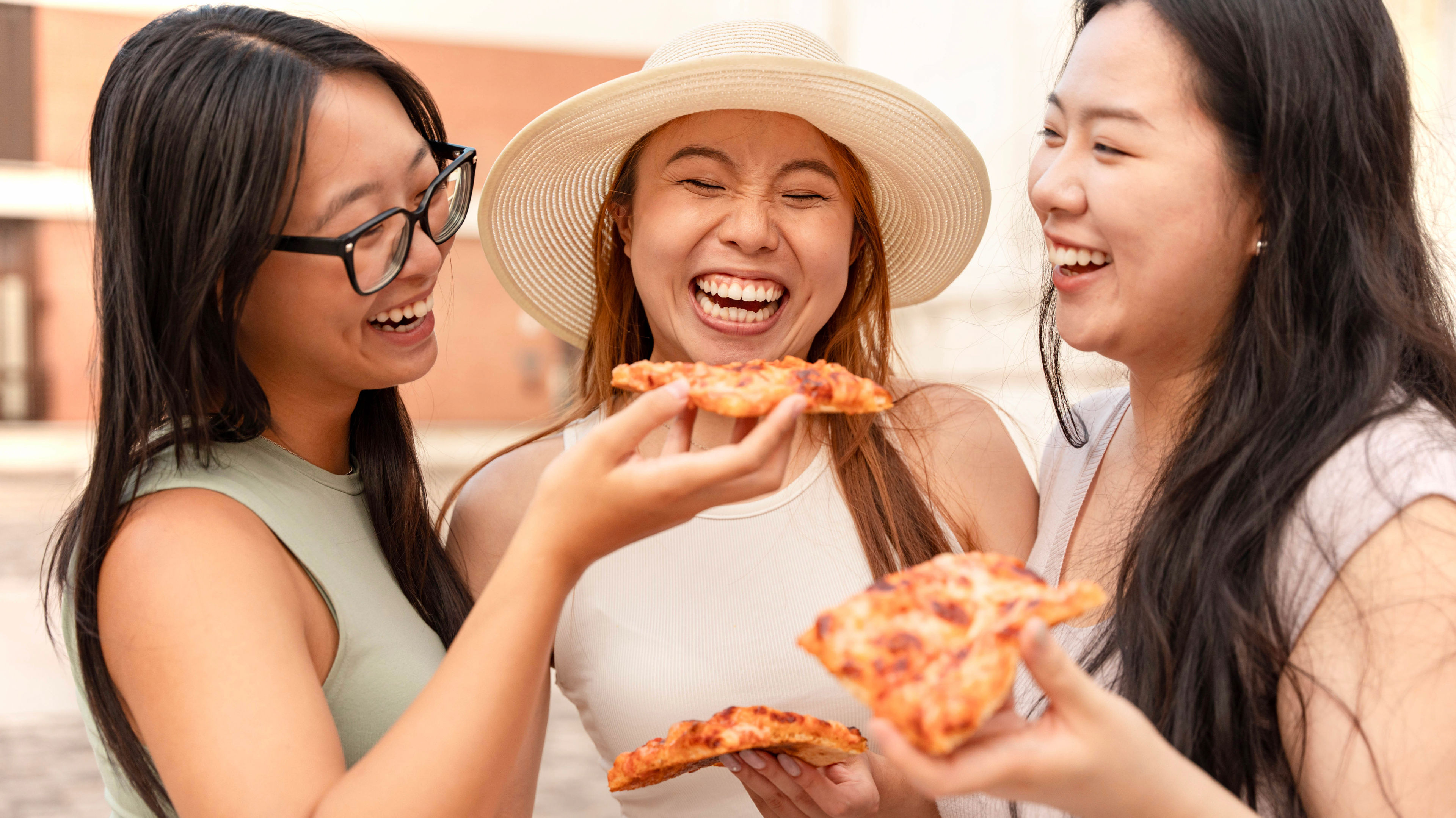 Three women smiling and eating Pizza