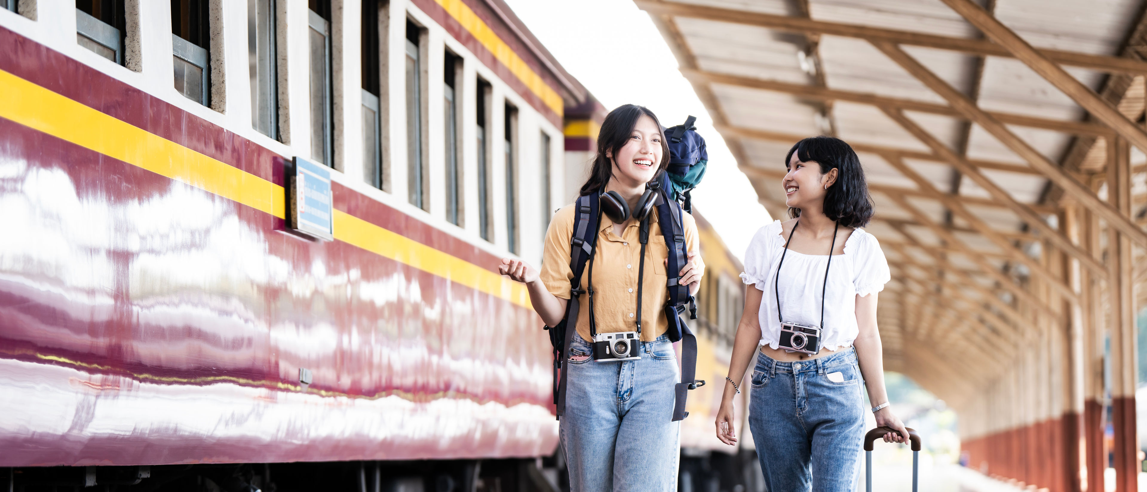 Two young Asian women with backpack walking together at Train Station Platform