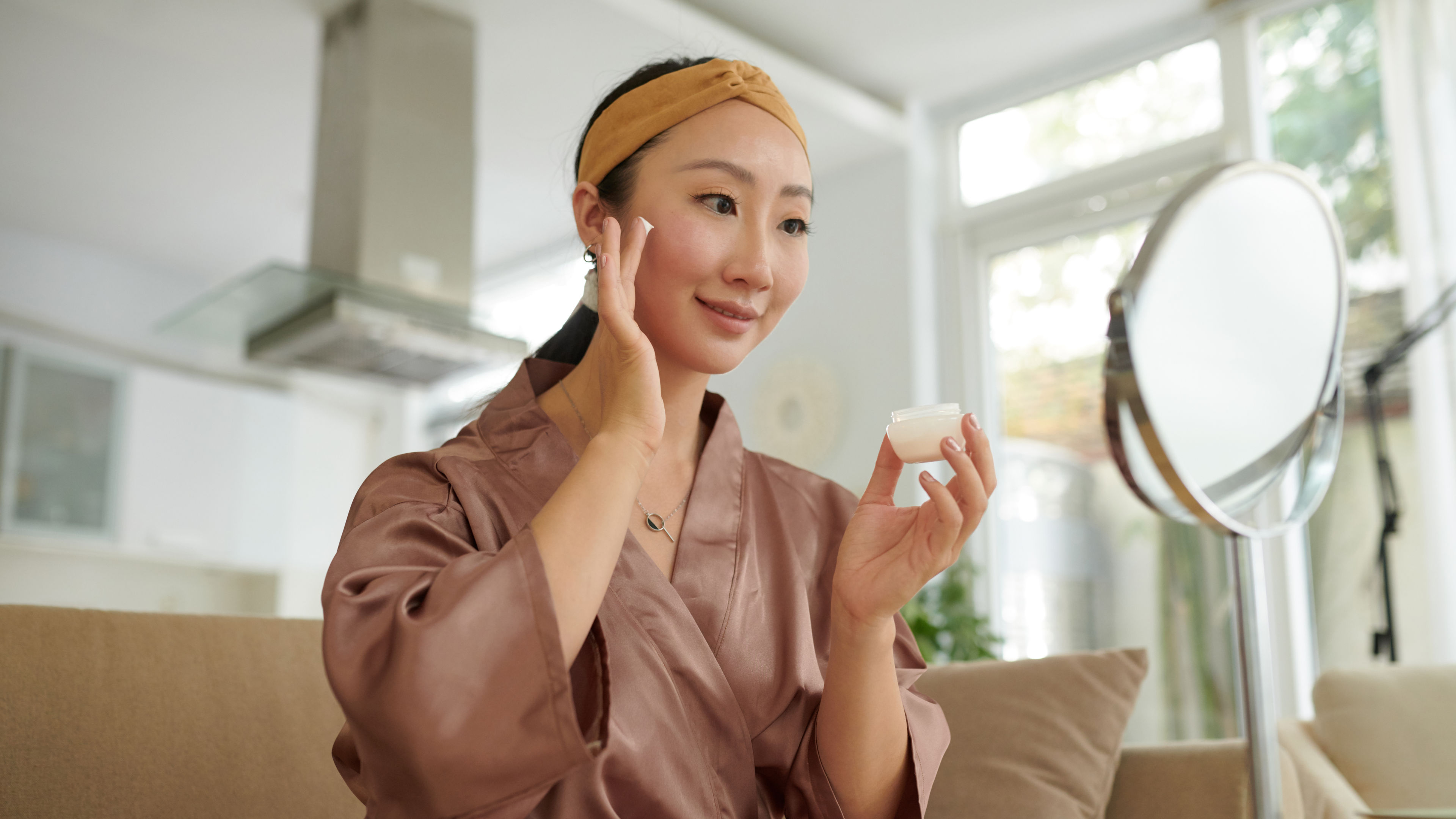 A woman is applying anti-aging cream to her face 