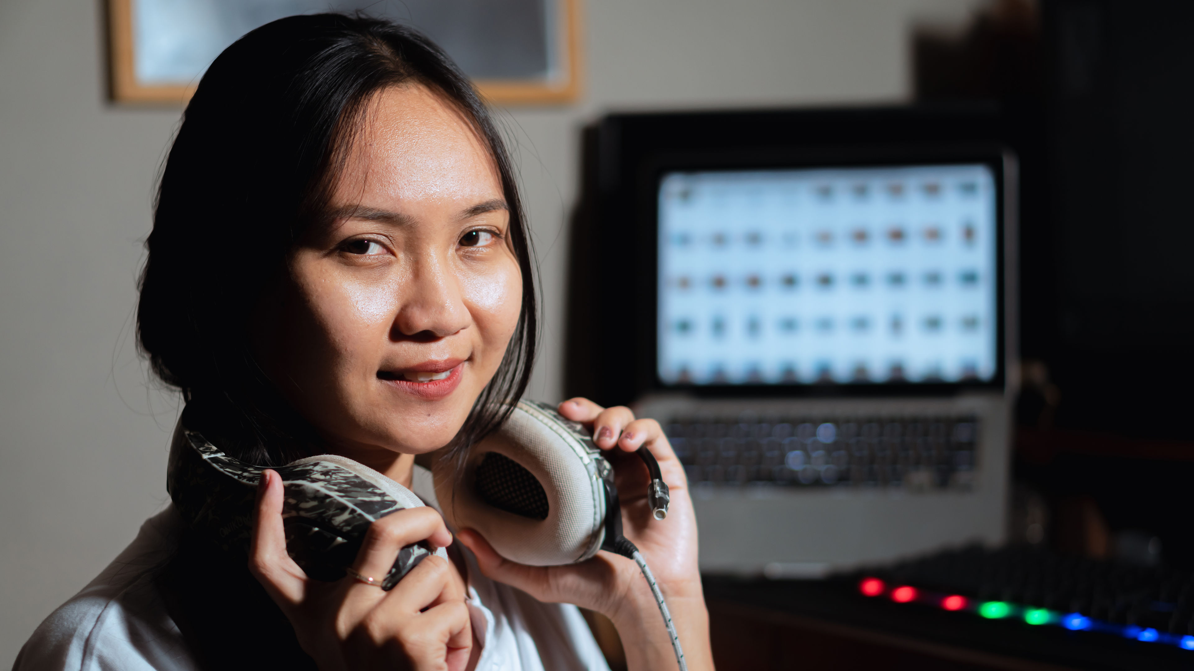 Babaeng naka headphone sa harap ng computer at sound mixer 

